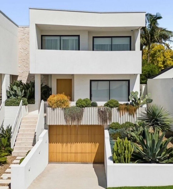 Contemporary white home with a timber garage door and garden